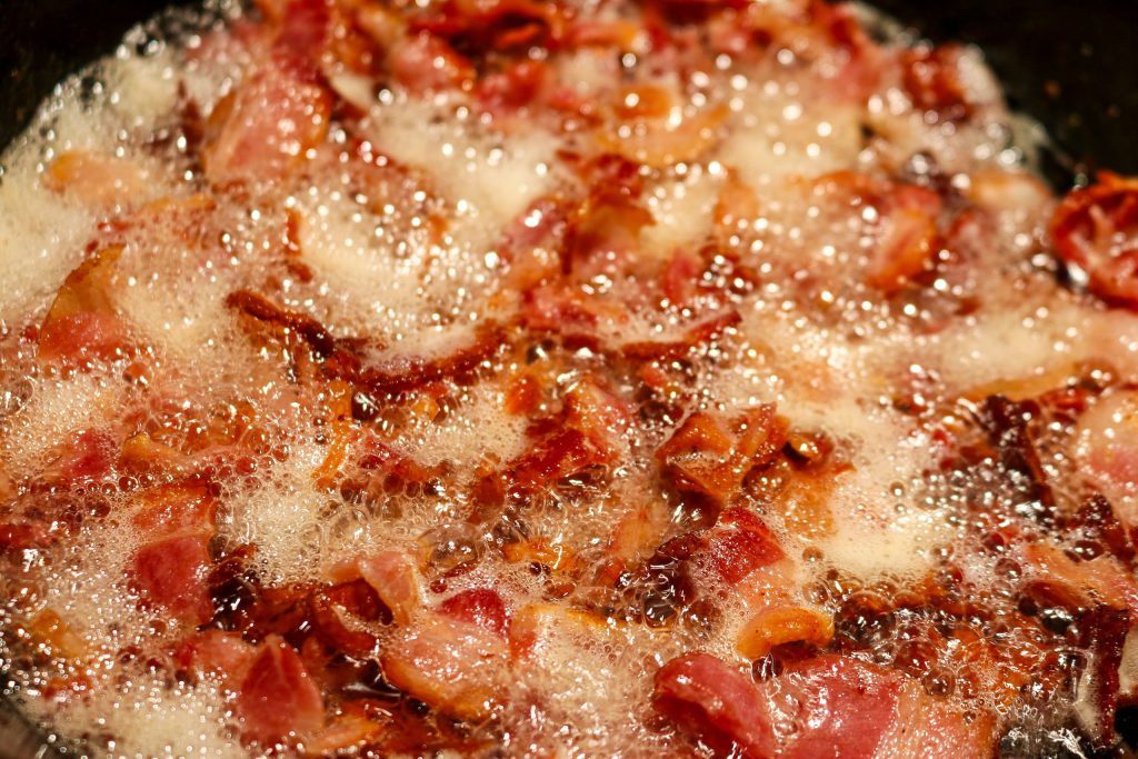 bacon pieces frying in a skillet 