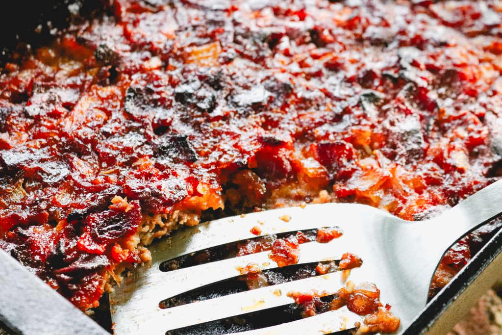 meatloaf in a cast iron skillet with a stainless steel spatula