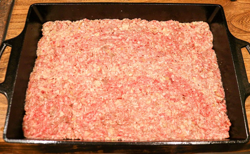 uncooked meatloaf in a cast iron baking dish