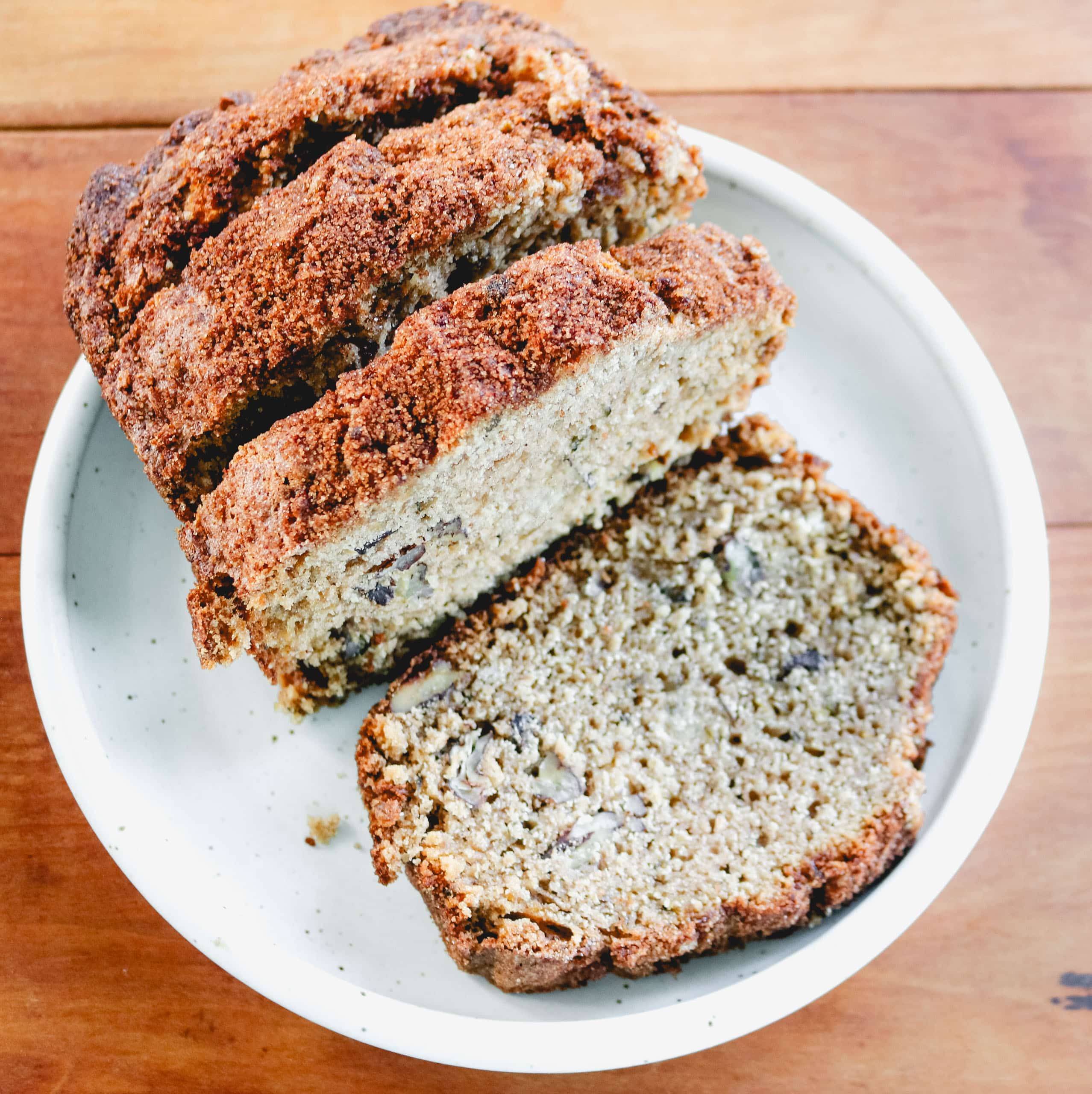 sliced zucchini bread on a white plate on a wooden counter