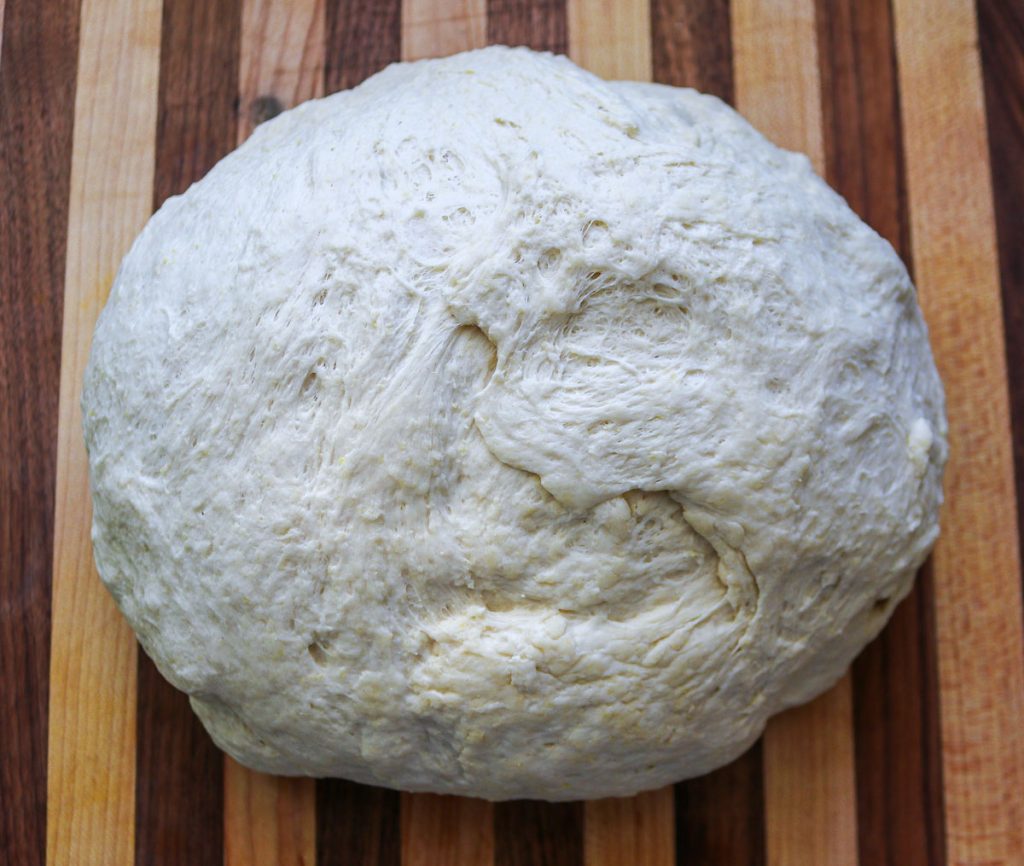 sourdough pizza dough on a wooden cutting board