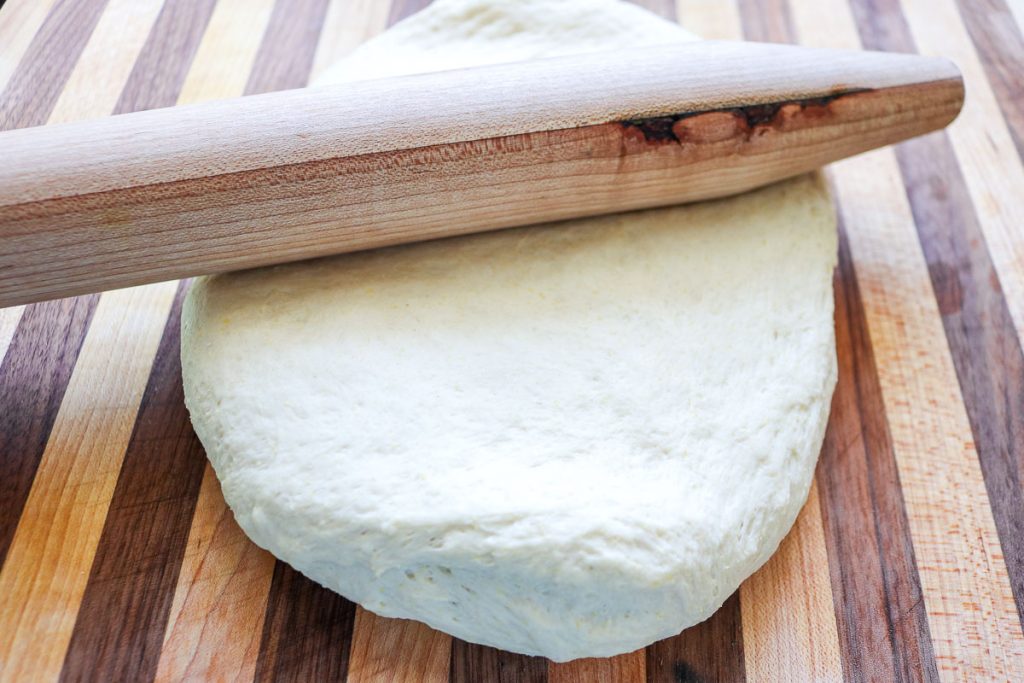 rolling pin on top of sourdough pizza dough ball