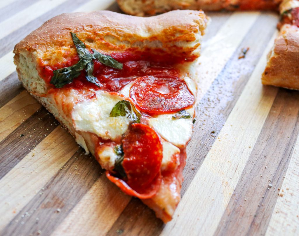 slice of pepperoni pizza on a wooden cutting board