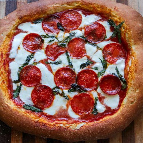 whole sourdough pepperoni pizza on a wooden cutting board