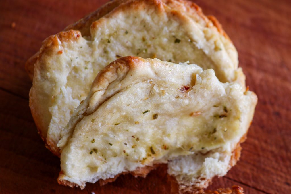 a piece of garlic pull apart bread on a wooden counter