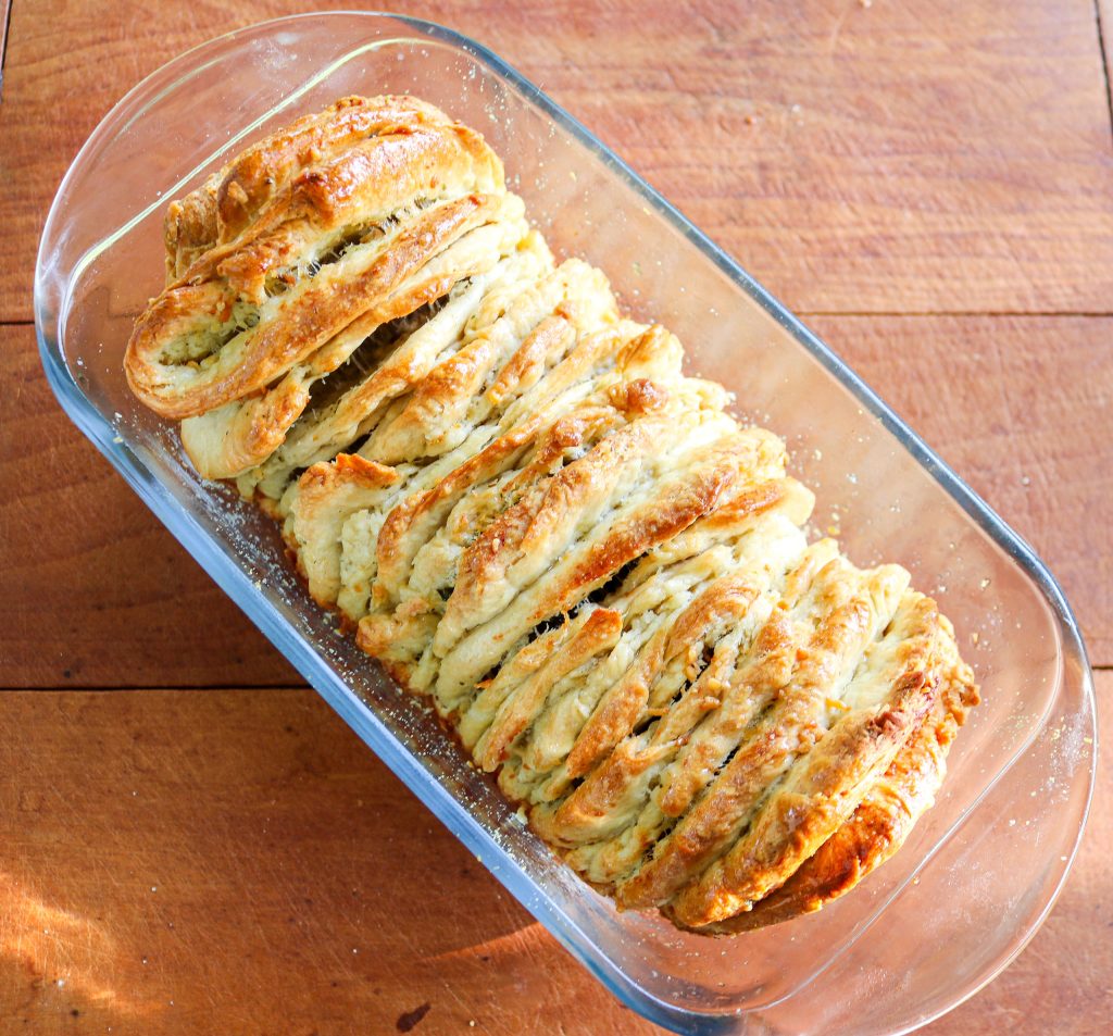 pull apart bread loaf in a glass bread pan on a wooden counter