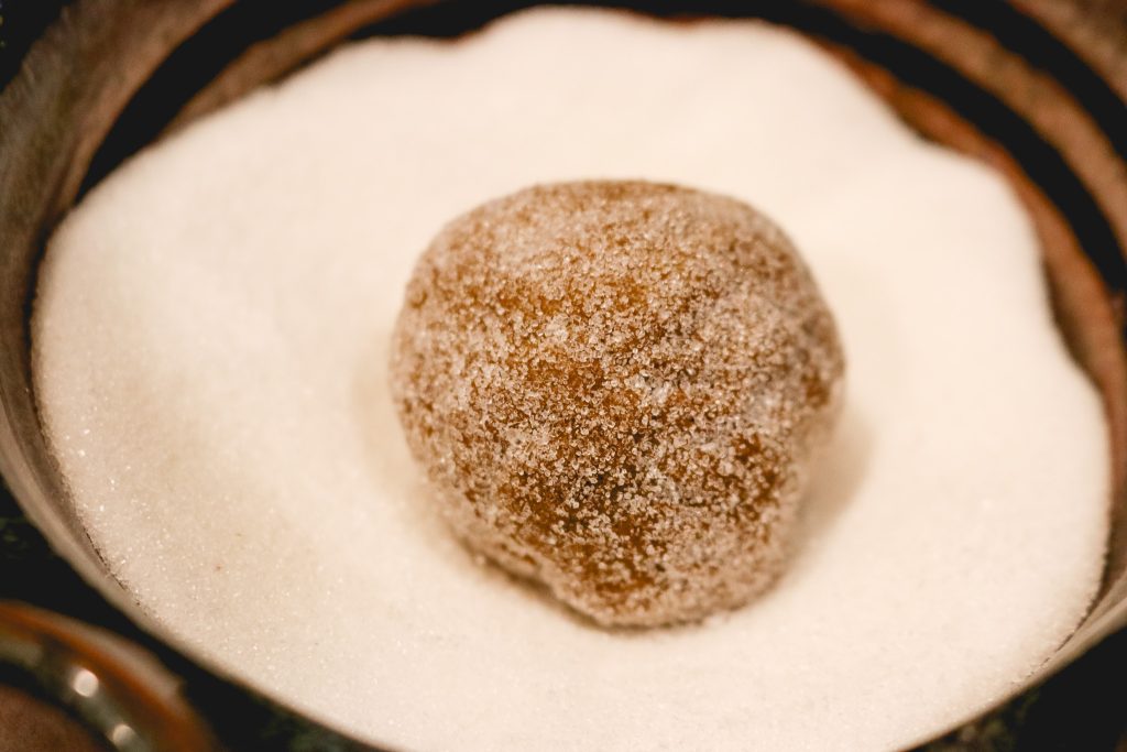 ginger cookie dough ball in bowl of sugar