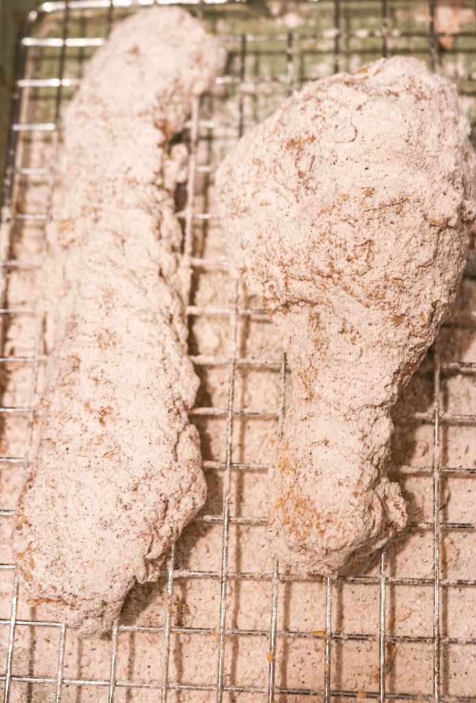 chicken tender and drumstick dipped in flour on a wire rack