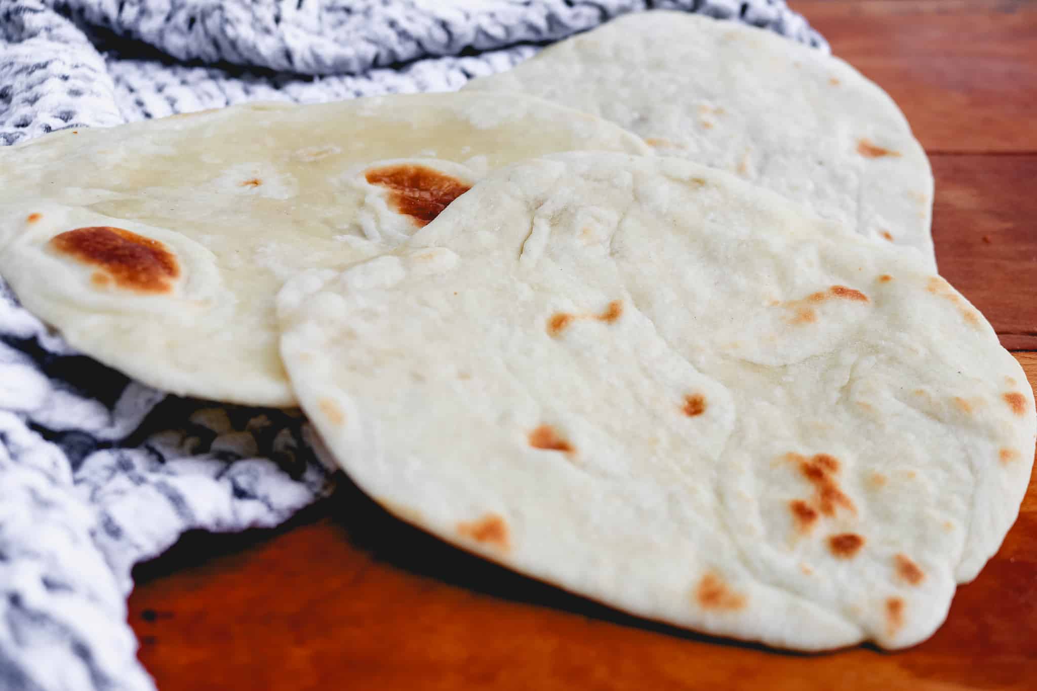 white flour tortillas on top of a black and white tea towel on a counter