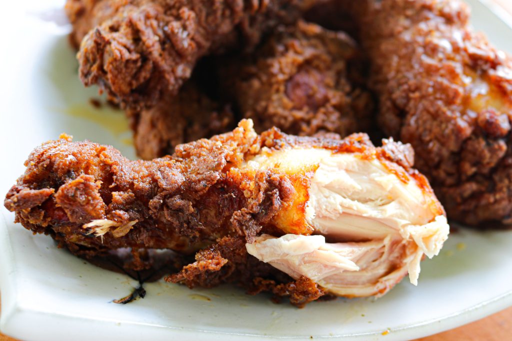 fried chicken on a plate with a drumstick with a bite taken out