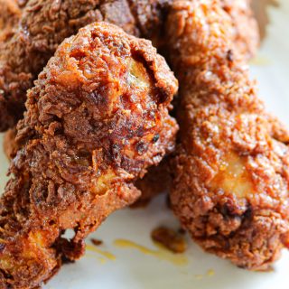 two fried chicken drumsticks with honey on a plate