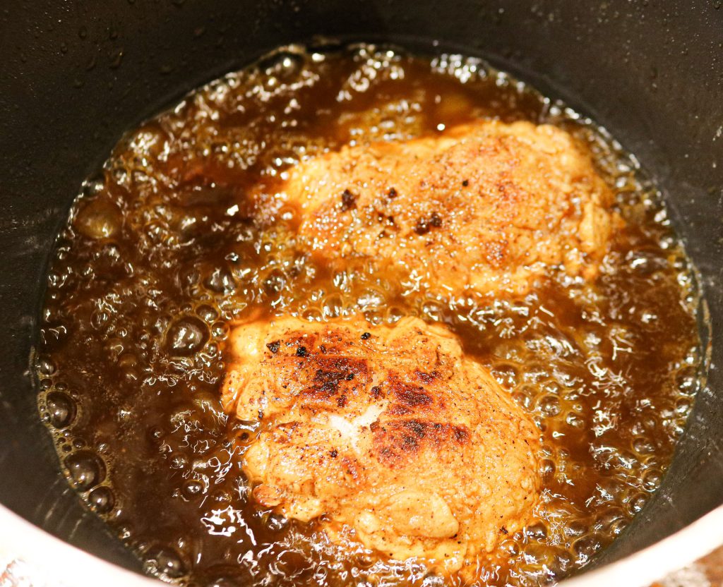 two chicken drumsticks frying in oil