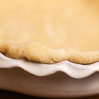 The edge of a fluted pie pan with an unbaked pie crust