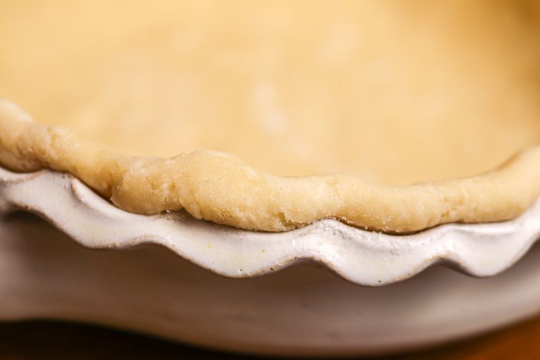 The edge of a fluted pie pan with an unbaked pie crust