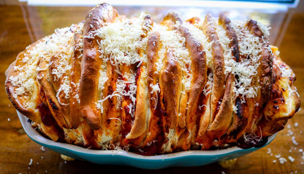 pull apart mozzarella bread with parmesan on top in a loaf pan on a wooden counter