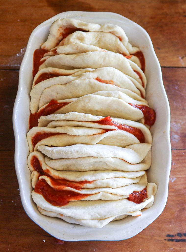 pull apart mozzarella bread in a loaf pan on a wooden counter