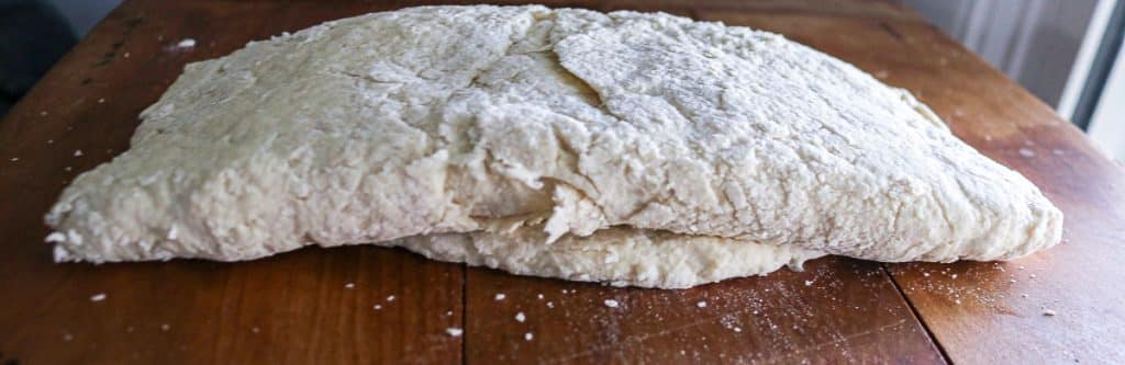 Folded sourdough biscuit dough creating layers for flaky biscuits.