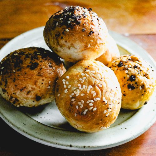 a stack of miniature bagels on a white plate