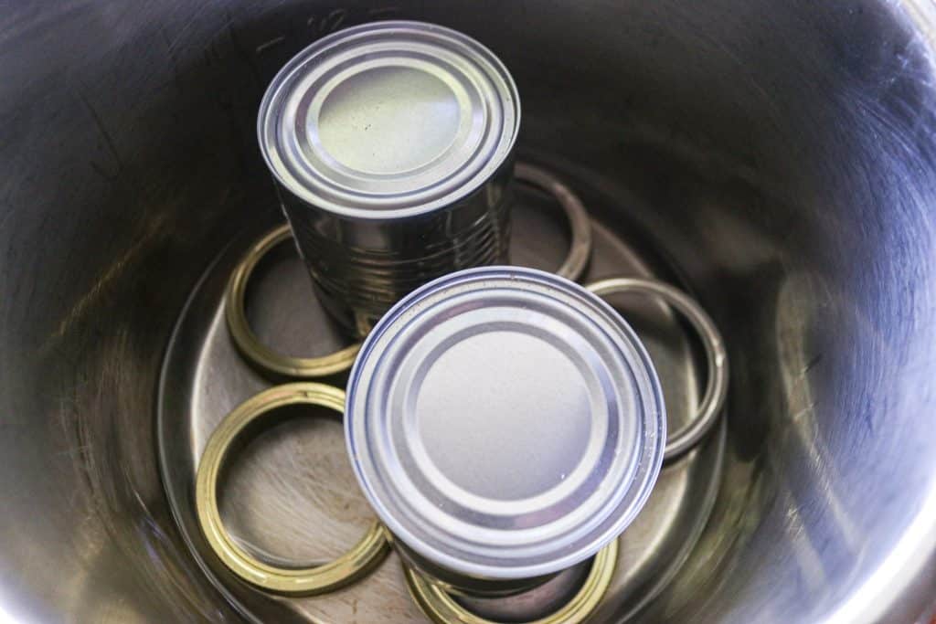 two cans in a instant pot on top of metal lids as a trivet