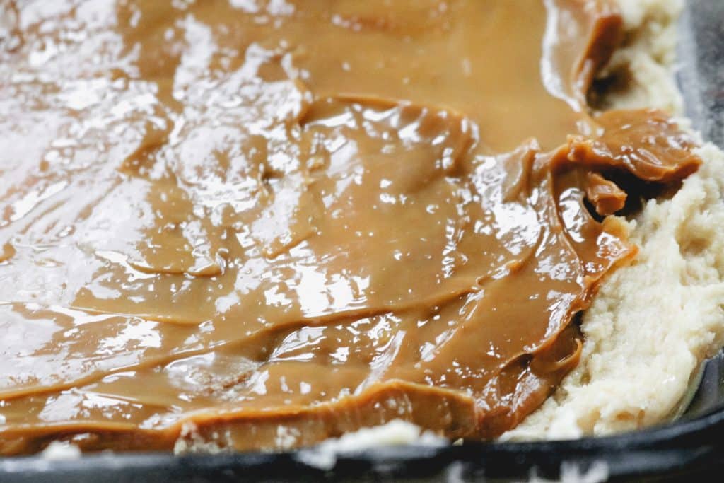 caramel spread over top of a shortbread crust in a glass pan