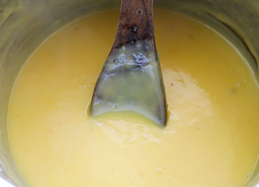 wooden spoon in a stainless bowl of vanilla pudding