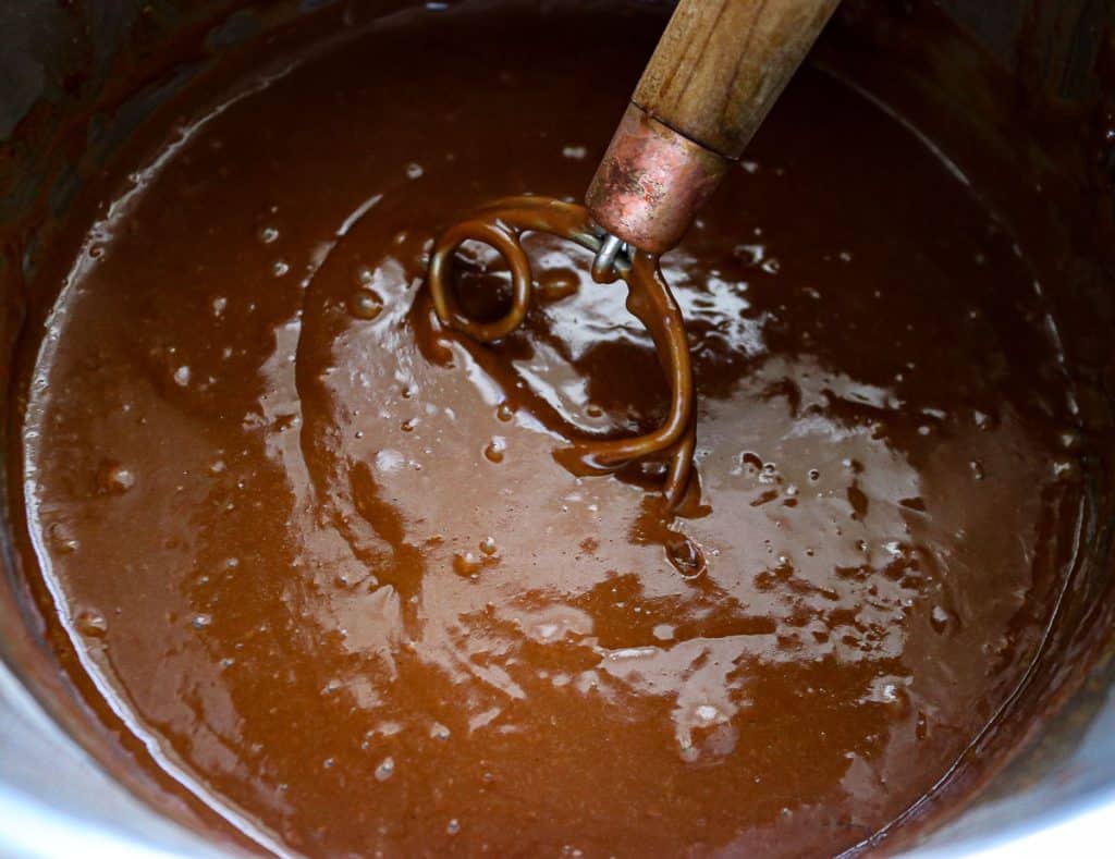 a bowl of chocolate pudding with a danish whisk in it