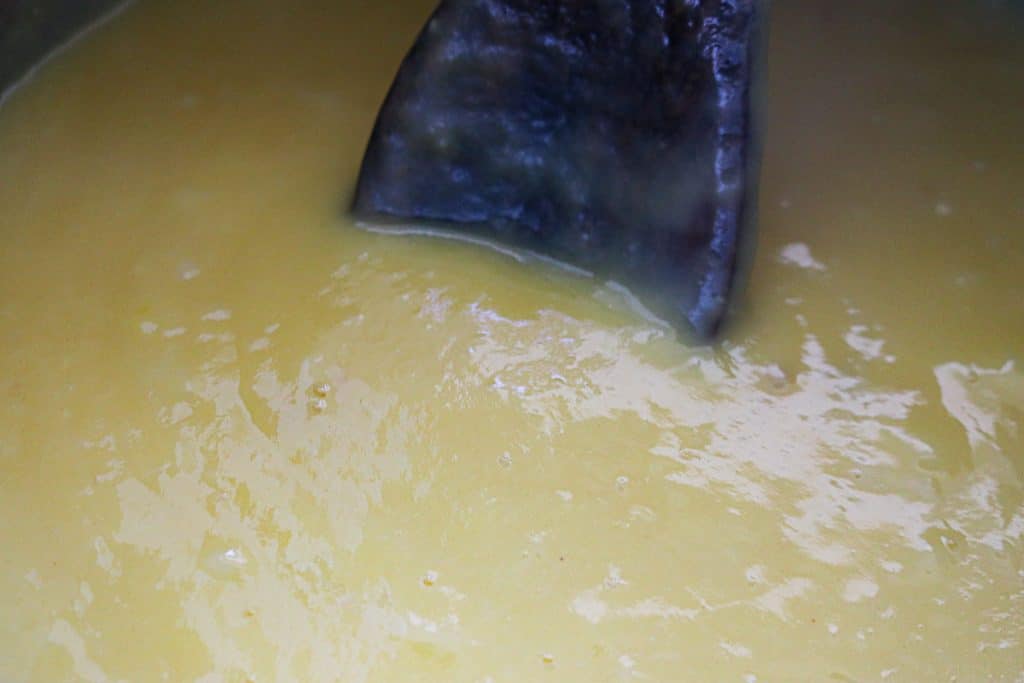 wooden spoon in a stainless bowl of vanilla pudding