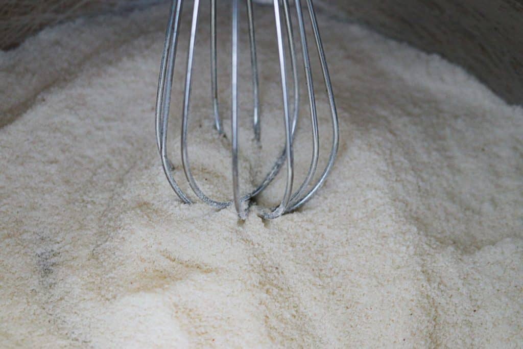 a whisk in a stainless steel bowl of dry vanilla pudding mix