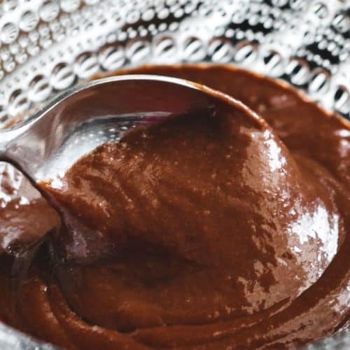 a spoon scooping chocolate pudding out of a crystal bowl