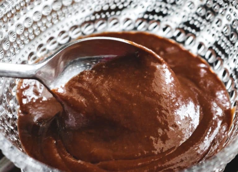 a spoon scooping chocolate pudding out of a crystal bowl