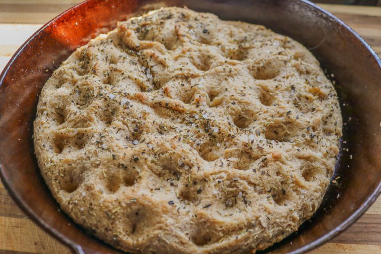 cast iron skillet of focaccia bread on a wooden counter