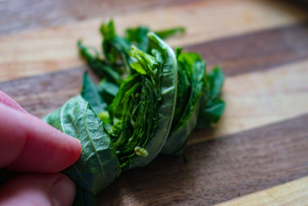 basil cut into ribbons on a wooden cutting board