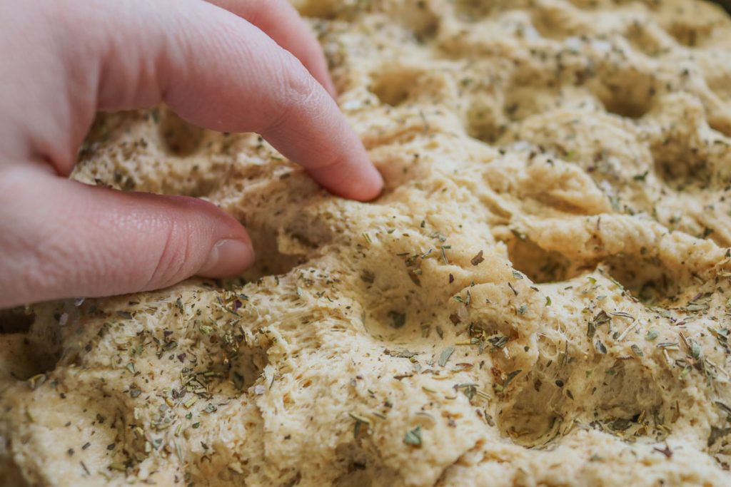 hands dimpling focaccia