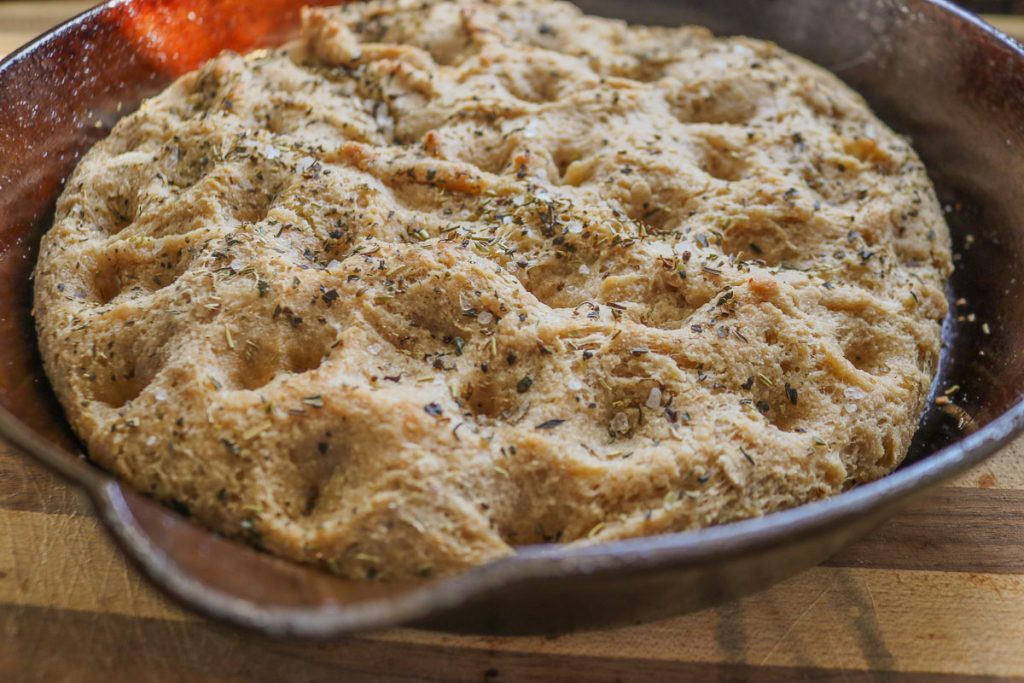 finished baked focaccia in a cast iron skillet with herbs