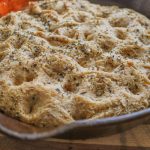 finished baked focaccia in a cast iron skillet with herbs