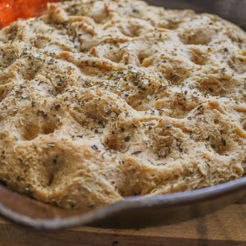 finished baked focaccia in a cast iron skillet with herbs