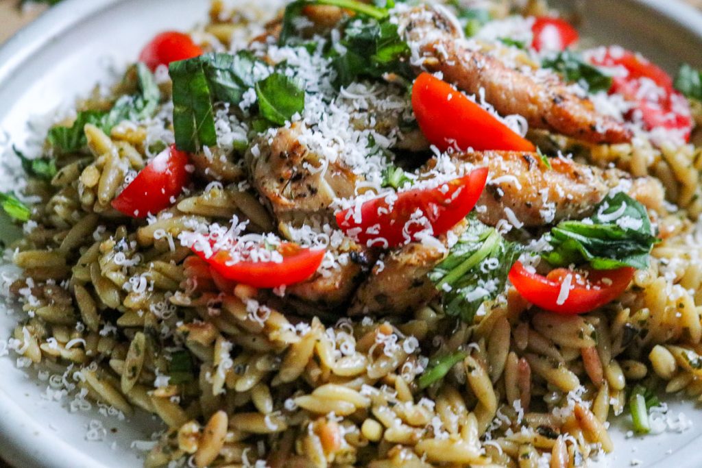 white plate of pesto orzo with chicken and tomatoes