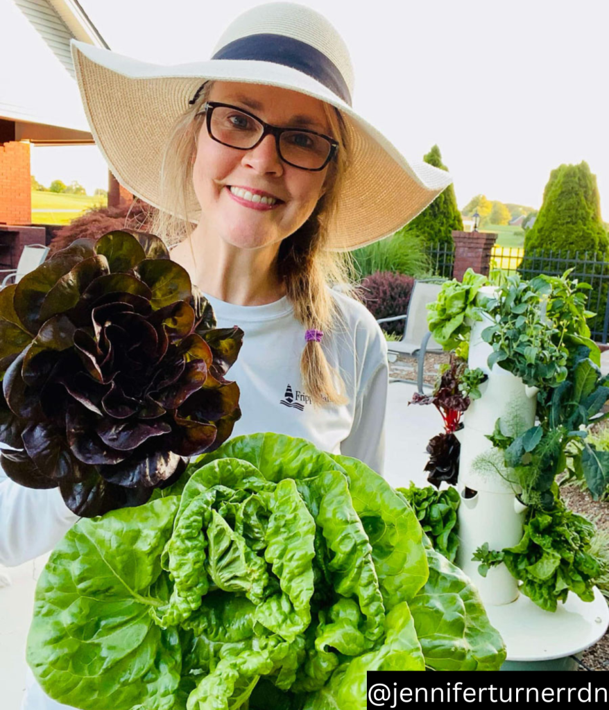 woman holding lettuces in front of Juice plus tower garden