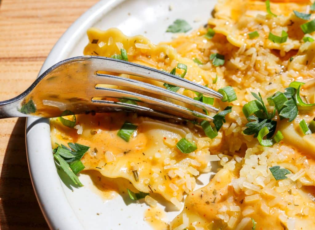 fork cutting into ravioli tossed in compound butter