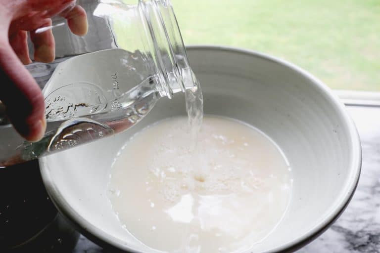pouring water out of a mason jar into a white bowl