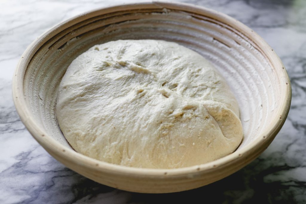 boule dough resting in proofing basket on a white counter