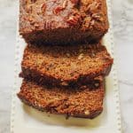 sliced banana bread on a white platter on a marble counter