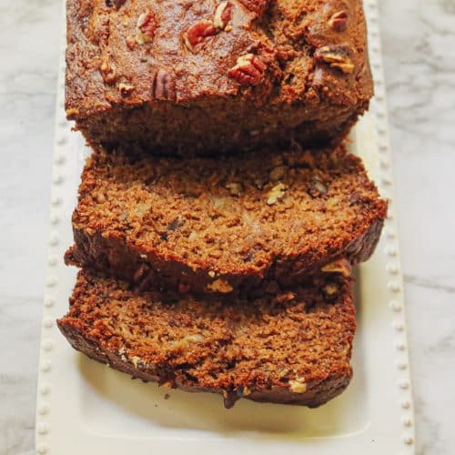 sliced banana bread on a white platter on a marble counter