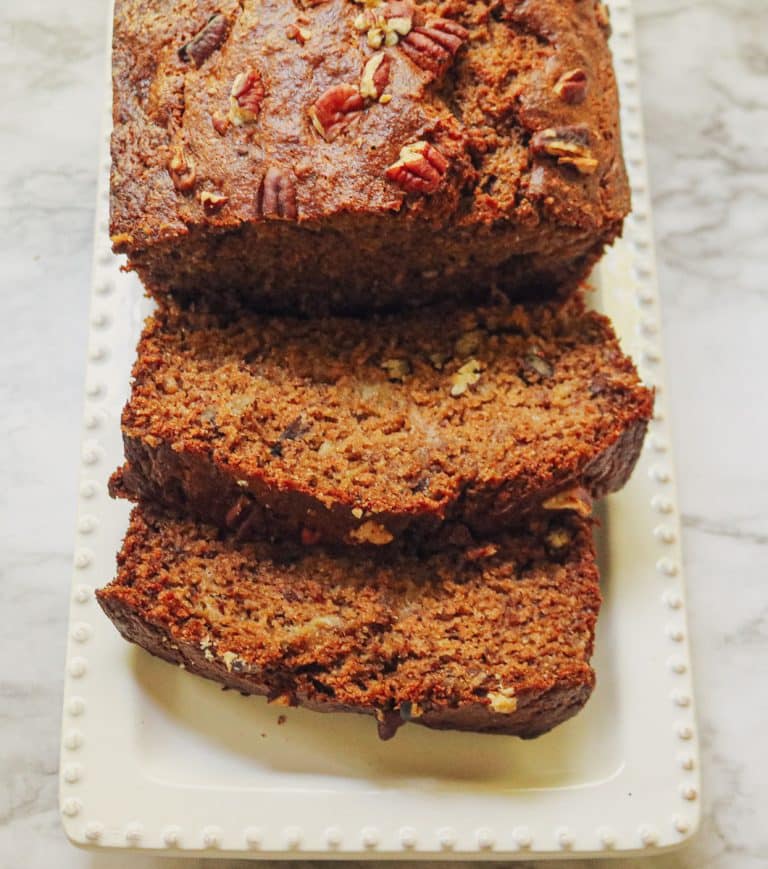 sliced banana bread on a white platter on a marble counter