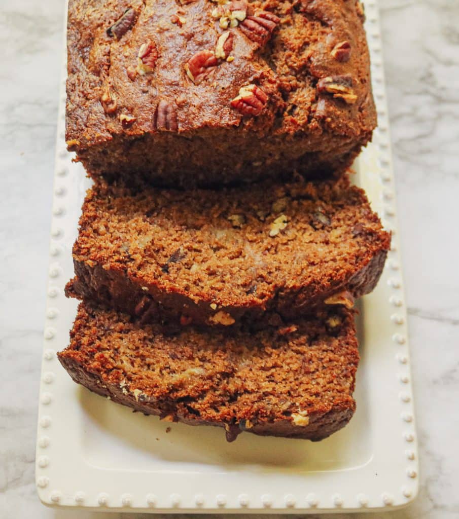 sliced banana bread on a white platter on a marble counter