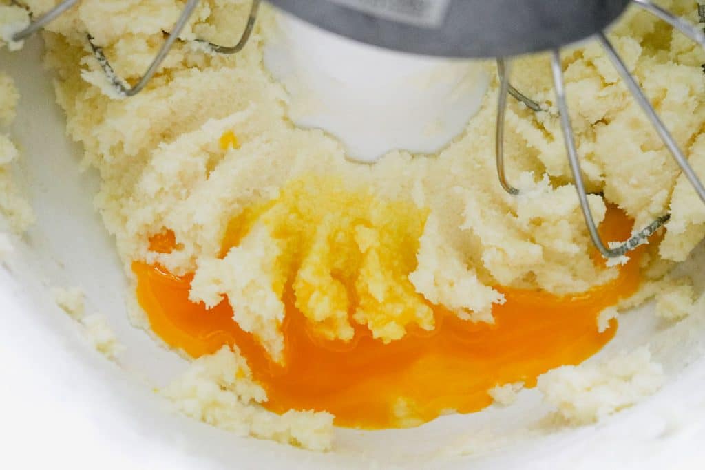 egg yolks mixing into creamed butter and sugar