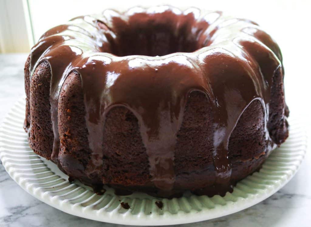 upclose shot of iced sourdough chocolate pound cake on a white plate