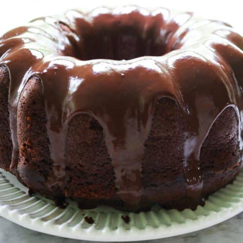 upclose shot of iced sourdough chocolate pound cake on a white plate