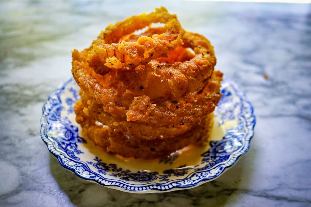 sourdough onion rings stacked on a blue and white plate