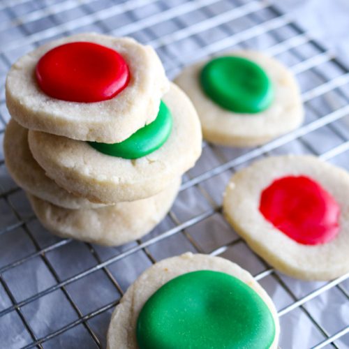 stack of red and green thumbprint cookies on a wire rack